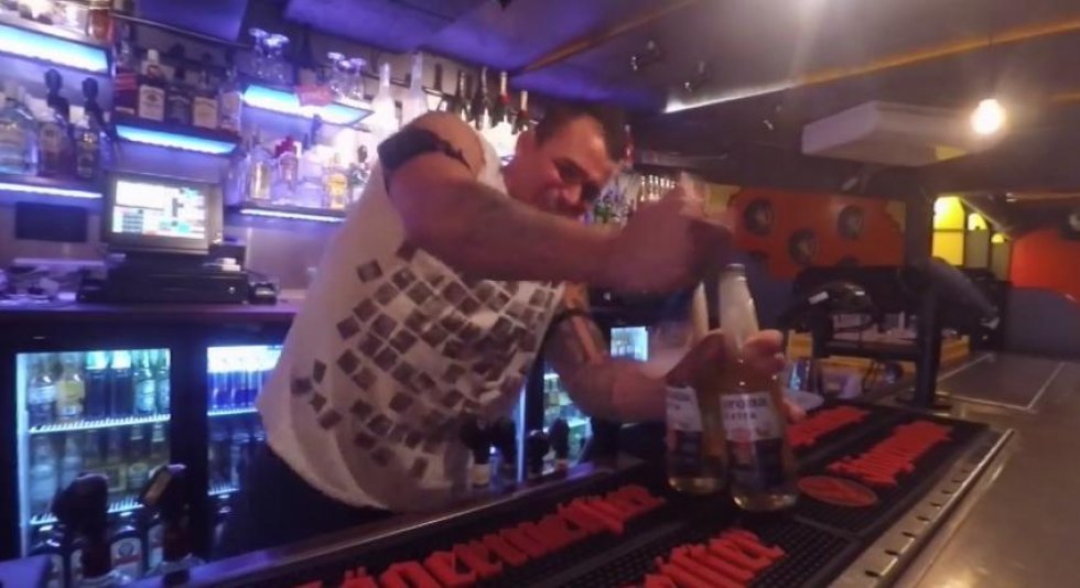 Bartender åbner øl, mens han får stød i armene