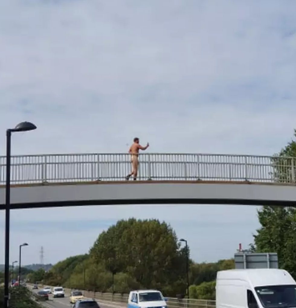 Mand spottet på motorvejsbro, mens han laver squats nøgen